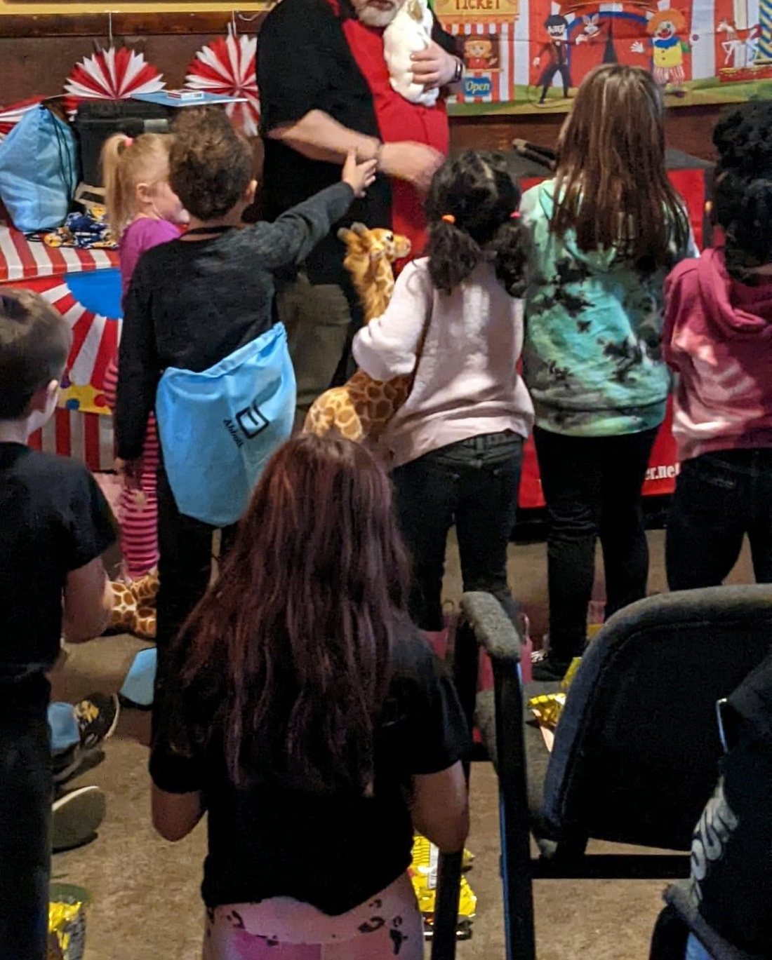 Children taking turns to pet the live rabbit with Carroll Baker at the end of a party show